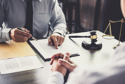 Lawyer discussing legal documents with a client in an office, with a gavel and scales of justice on the desk