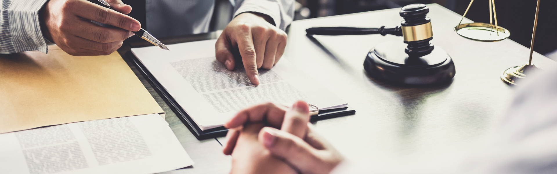 Lawyer discussing legal documents with a client in an office, with a gavel and scales of justice on the desk