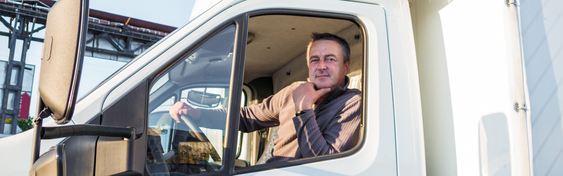 a truck driver sitting in the cab of a white truck